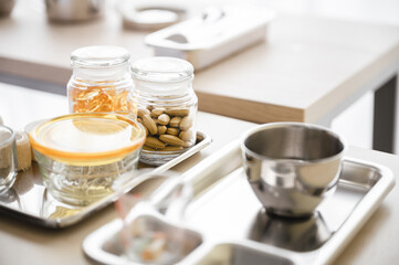 Bottle of supplement capsules is placed in a tray on a table against a blurred background. Health care concept.