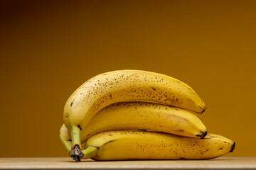 Low key still life of a couple of overripe bananas with black spots and bright yellow parts...