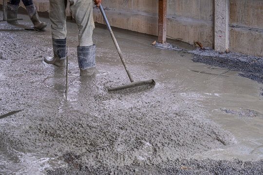 worker man dirty working wet cement  on floor by use trowel with long Tools spreading poured concrete for strong street after dry.