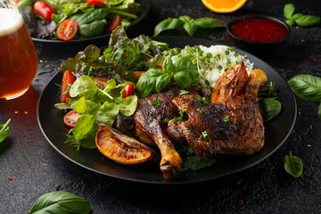 Slow cooked aromatic duck legs with basmati rice and side salad served with orange wedges on black plate