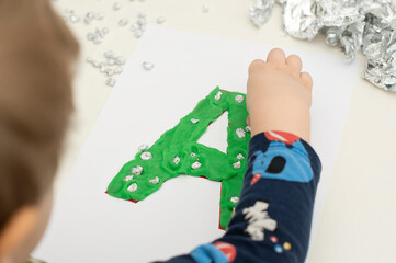 Two year boy decorating play dough letter 