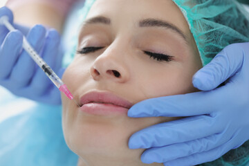 Doctor cosmetologist giving injection to young woman in clinic