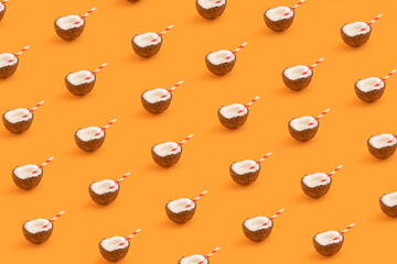 Pattern made with coconut with colored straw on orange background