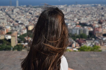 Mujer mirando al horizonte en Barcelona con la ciudad de fondo en un día con viento mientras su...