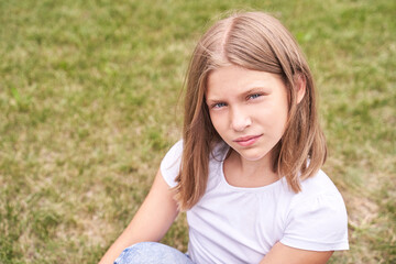 Fototapeta na wymiar Little girl portrait. Outdoor green background. Looking. Teenager schoolgirl at park. Cute face. Children beauty. Female head. Charisma caucasian