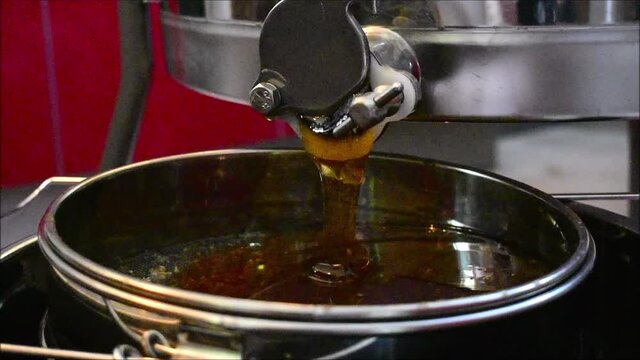 Honig flie&szlig;t aus der Honigschleuder, Waldhonig und Bl&uuml;tenhonig dunkel golden aus dem Auslass