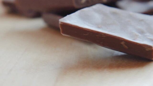 Homemade chocolate bars with nuts in soft focus at high magnification. Rotating background with broken craft chocolate bars