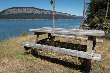 Weathered and worn wooden picnic table at shoreside camping site.