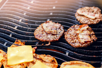 Cook grills burger patties and cheese pork ribs open fire. Turns meat over with tongs