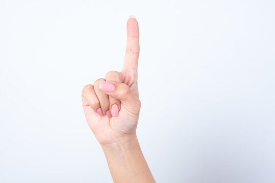 Woman's hand with pink manicure over isolated white background pointing up with finger number one. 