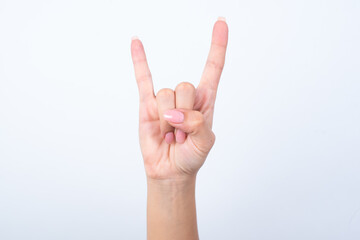 Woman's hand with pink manicure over isolated white background making rock gesture showing horns.
