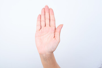 Woman's hand with pink manicure over isolated white background showing open palm making stop gesture.