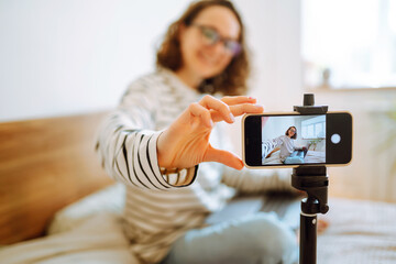 Young woman recording her video blog. Woman blogger videotapes her vlog at home. Vlogger makes...