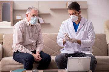 Young male doctor visiting old patient in vaccination concept