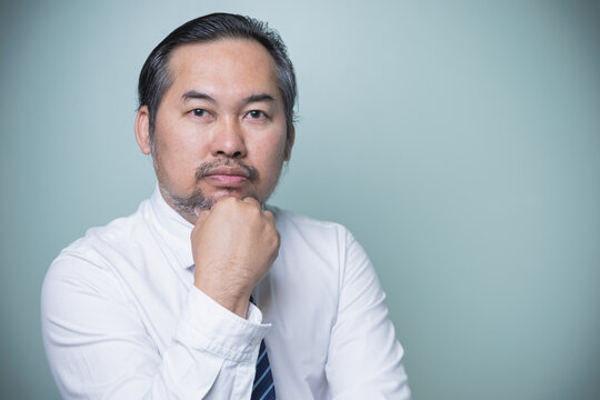 Portrait Asian businessman wears a white shirt with tie blue looking at the camera have high self-confidence standing thinking about business to the future on green background with copy space.