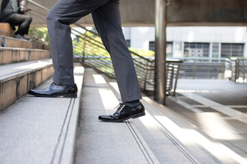 Business and grow up concept. Close up legs business man holding briefcase and walking up stairs...