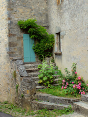 Obraz na płótnie Canvas Fresh green plants and flowers around rustic old doors of charming country-style grey stone medieval houses in Vezelay village, Burgundy, France, a popular European tourist destination.