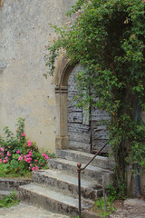 Fototapeta na wymiar Fresh green plants and flowers around rustic old doors of charming country-style grey stone medieval houses in Vezelay village, Burgundy, France, a popular European tourist destination.