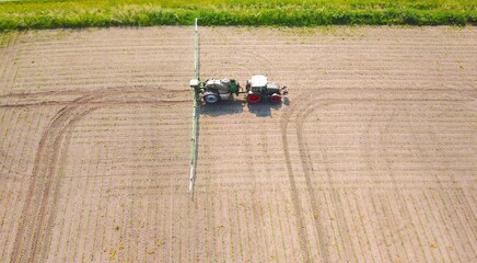 Traktor mit Feldspritze versprüht Pestizide auf Maisacker, Landwirtschaft, Vogelperspektive	
