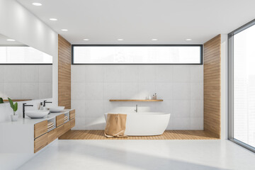 White bathtub in panoramic white bathroom interior with narrow window