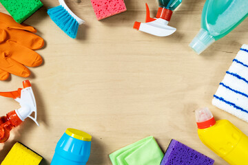 Cleaning concept. Frame of cleaning supplies on wooden background, top view