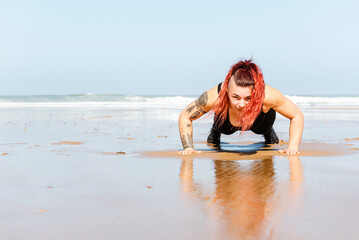 Fit sportswoman doing push ups on wet shore against sea