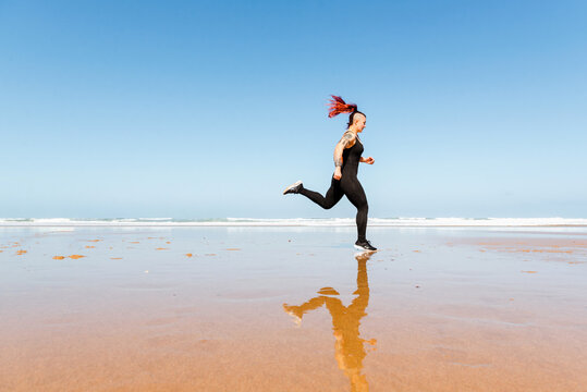 Fast runner jogging on sandy sea beach during workout