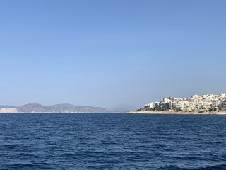 Greek city and mountains in the distance from ocean with blue skies