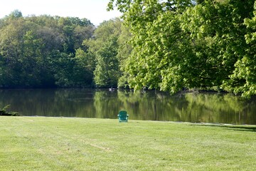 The empty chair near the lake in the park on a sunny day.