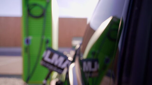 Elektroauto steht an der Tankstelle bzw. Aufladestation f&uuml;r Elektroautos und Hybridfahrzeuge und l&auml;dt die Akkus mit Strom aus umweltfreundlicher erneuerbarer Sonnenenergie auf. 