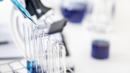 Scientist dropping a sample into a test tube with dropper in pharmaceutical research laboratory. Innovation Concept.