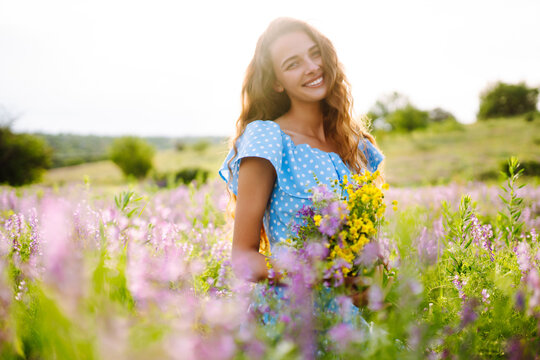 Portrait of beautiful woman in amazing in a blooming field. Nature, vacation, relax and lifestyle. Summer landscape.