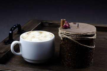 Cup of cappuccino coffee on a wooden table tray. Candle. Breakfast