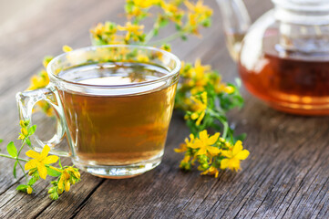 Glass cup of st john’s wort tea with flowers, herbal hot drink concept