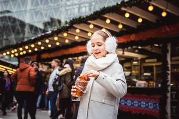 A cute little girl eats a traditional Hungarian sweet pastry called Kurtoskalacs in Budapest on the street market at wintertime