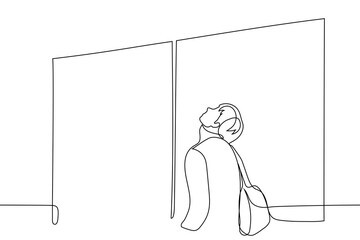 man stands in front of closed doors with a backpack on his back, his face pointing up - one line drawing vector. concept of impatient passenger waiting for boarding start