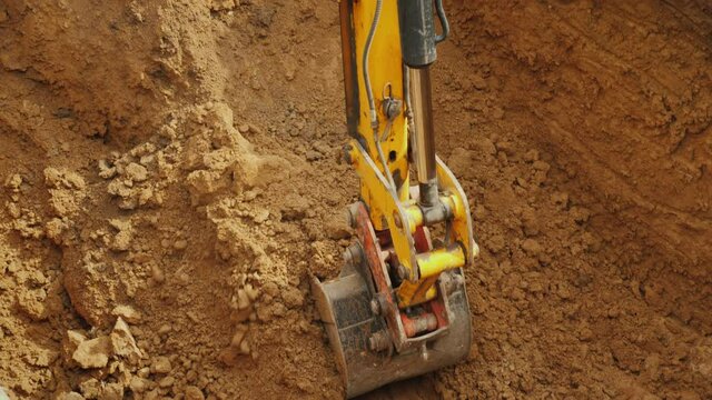 Large digger bucket extracts soil from trench