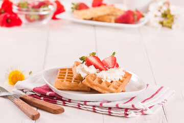 Waffles with strawberries and whipped cream.