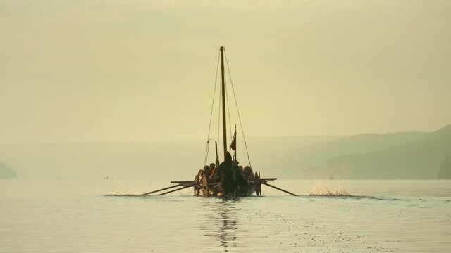 Medieval Ship with Vikings on Board Sails in the Middle of the River in a Magical Fog to new Shores. Concept of Romanticism.