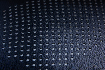 Abstract texture black artificial leather with holes, close-up. Abstract background