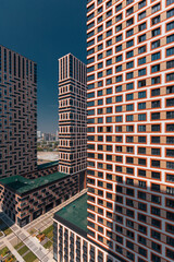 A capture in vertical format of a modern residential area with a pedestrian zone and a geometric pattern of paving slabs with green lawns surrounded by tall houses