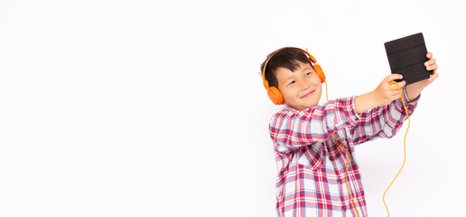 Portrait of litle boy playing at tablet and wearing headphones on white backgrond banner copy space