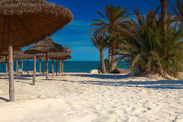 View of the white sand beach and parasols on the Mediterranean coast with birch water.