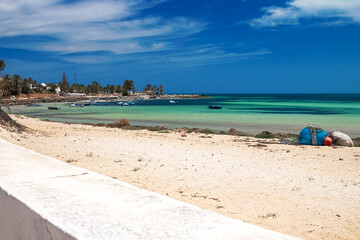 A beautiful view of the Mediterranean coast with birch water, a beach with white sand and a green palm tree.