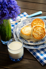 Cheesecakes or Syrniki on a plate. Russian and Belarussian cuisine, cornflowers decoration