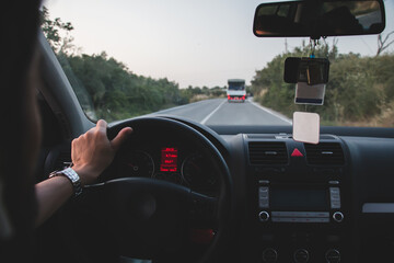 man holding steering wheel with one hand drives on empty road. Driving with one hand is dangerous.