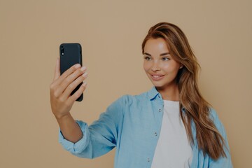 Adorable female model poses for making selfie in studio