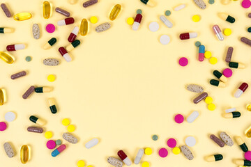 Frame of multicolored pills on a yellow background. Flat lay with copy space. 