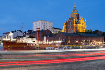 Obraz premium Beautiful night cityscape with illuminated Uspensky Cathedral in the background. An old lighthouse boat in the foreground.