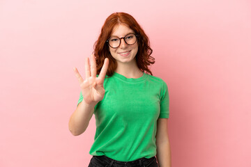 Teenager redhead girl over isolated pink background happy and counting four with fingers